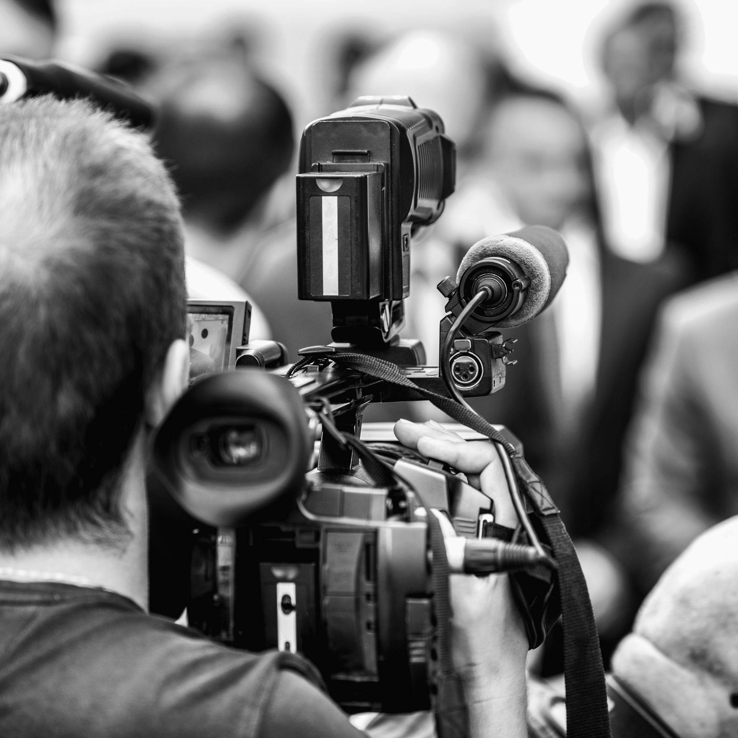 Camera operator working at a press conference outdoors. Journalists interviewing formal dressed politician or businessman at a media event.